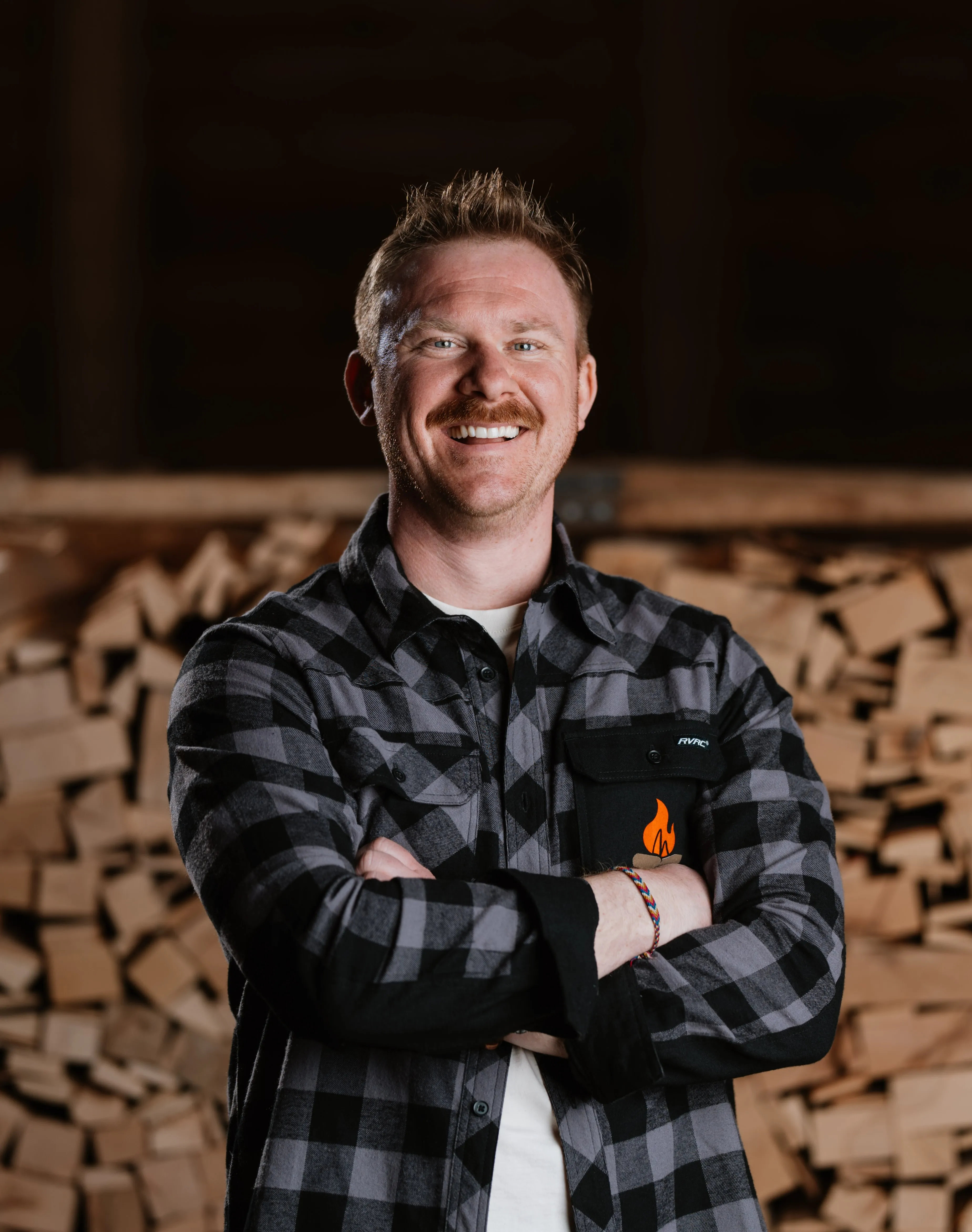 Professionelles Business Portrait — Mann im Flanellhemd vor Holzstapel, Perlesreut