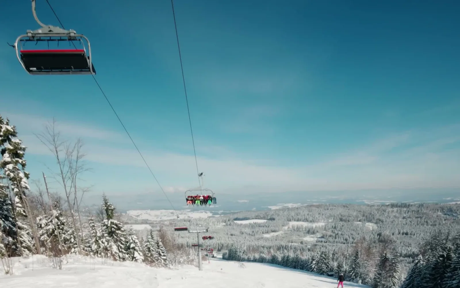 Sessellift am Geisskopf über der verschneiten Piste mit Blick über den Bayerischen Wald