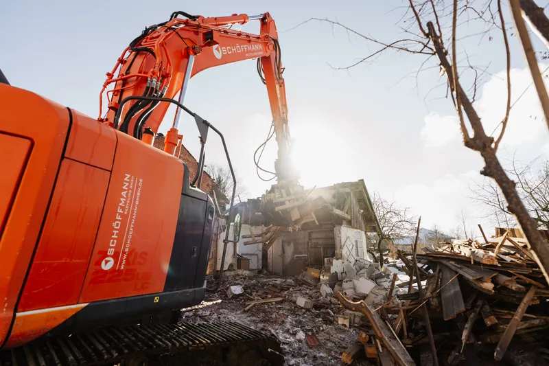 Bagger im Gegenlicht über dem Abbruchmaterial