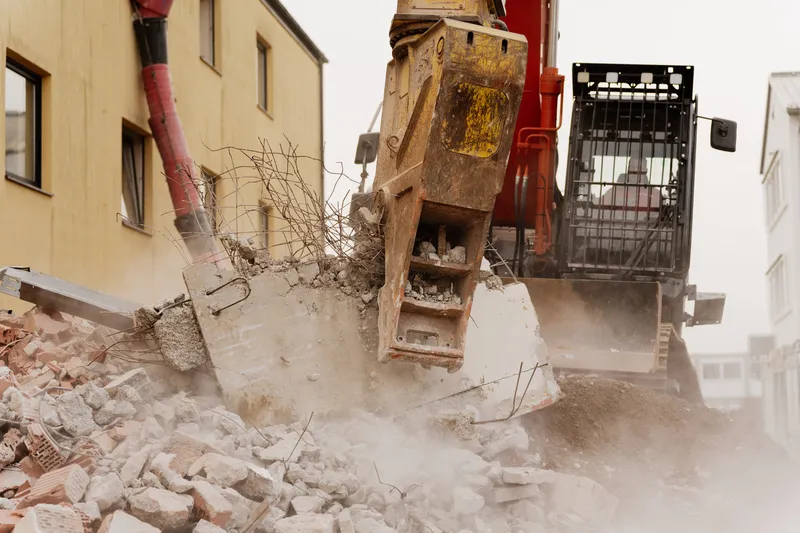 Bagger schiebt Bauschutt zusammen
