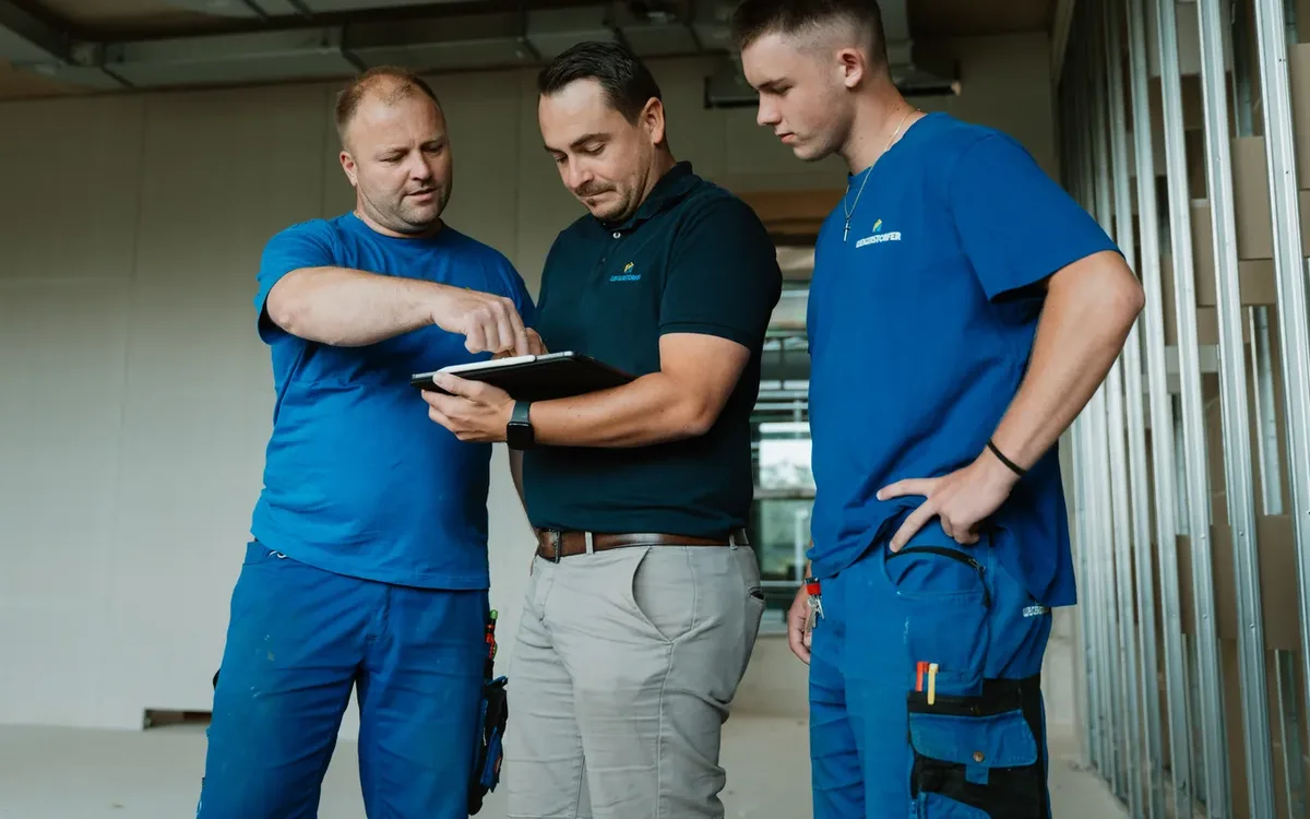 Drei Mitarbeiter der Weigerstorfer GmbH besprechen etwas auf einem Tablet