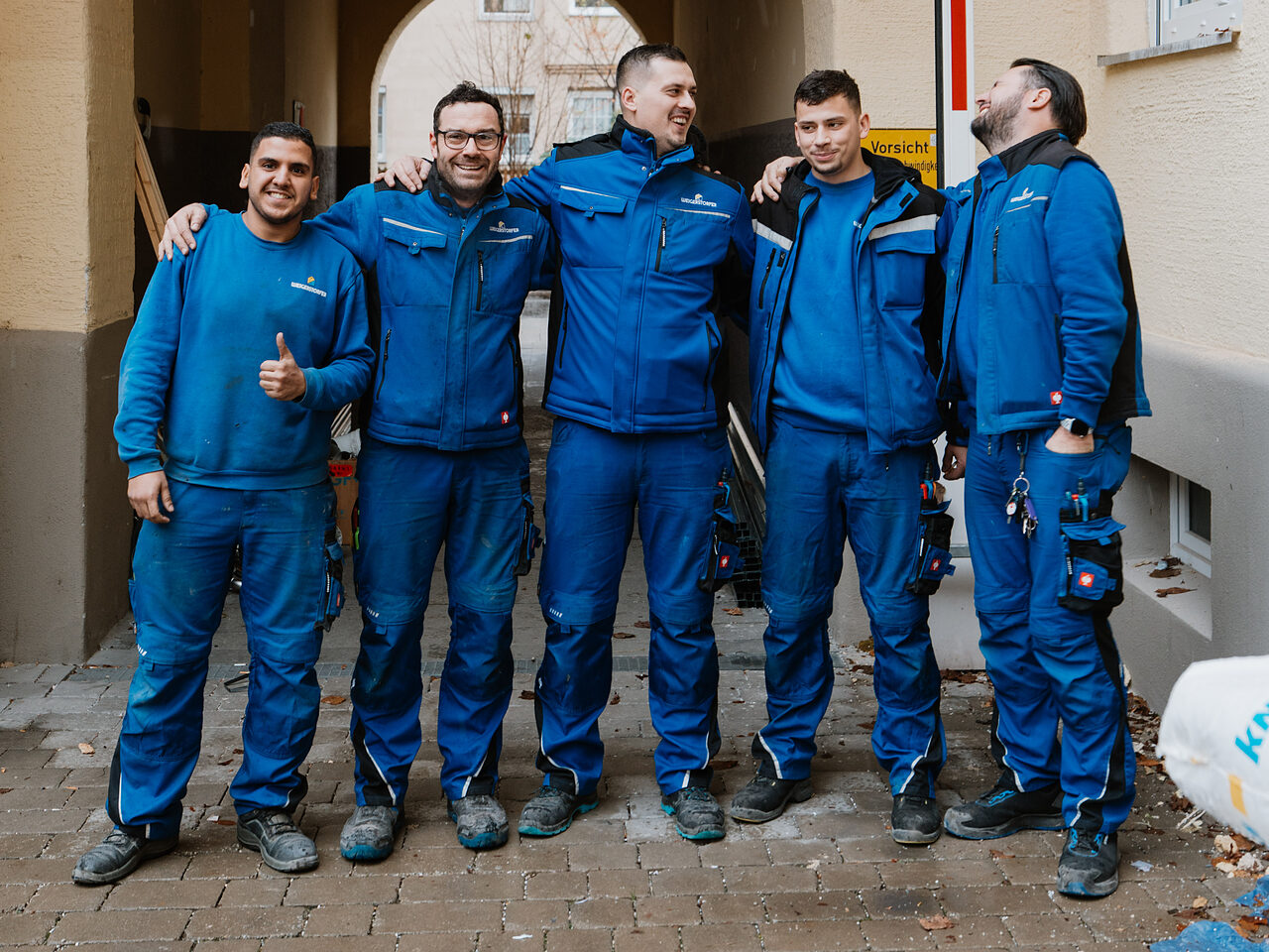 Fünf Handwerker der Weigerstorfer GmbH in blauer Arbeitskleidung – Mitarbeitergewinnung für Betriebe in Augsburg